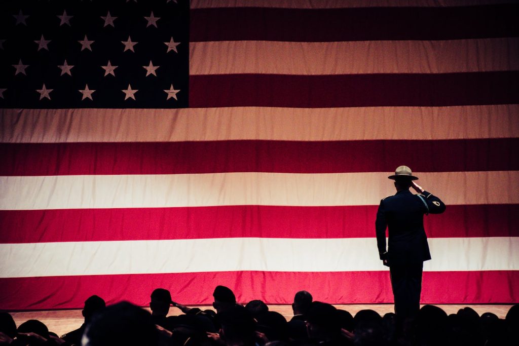 army spouse scholarship, Man Standing On Stage Facing An American Flag