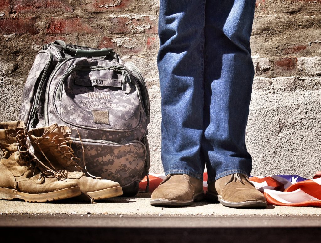 Military scholarship. minimalist photography of person standing near backpack and boots